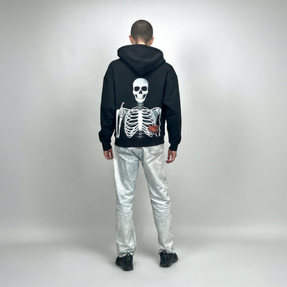 Person wearing a black hoodie with a skeleton design on the back, standing against a plain background.